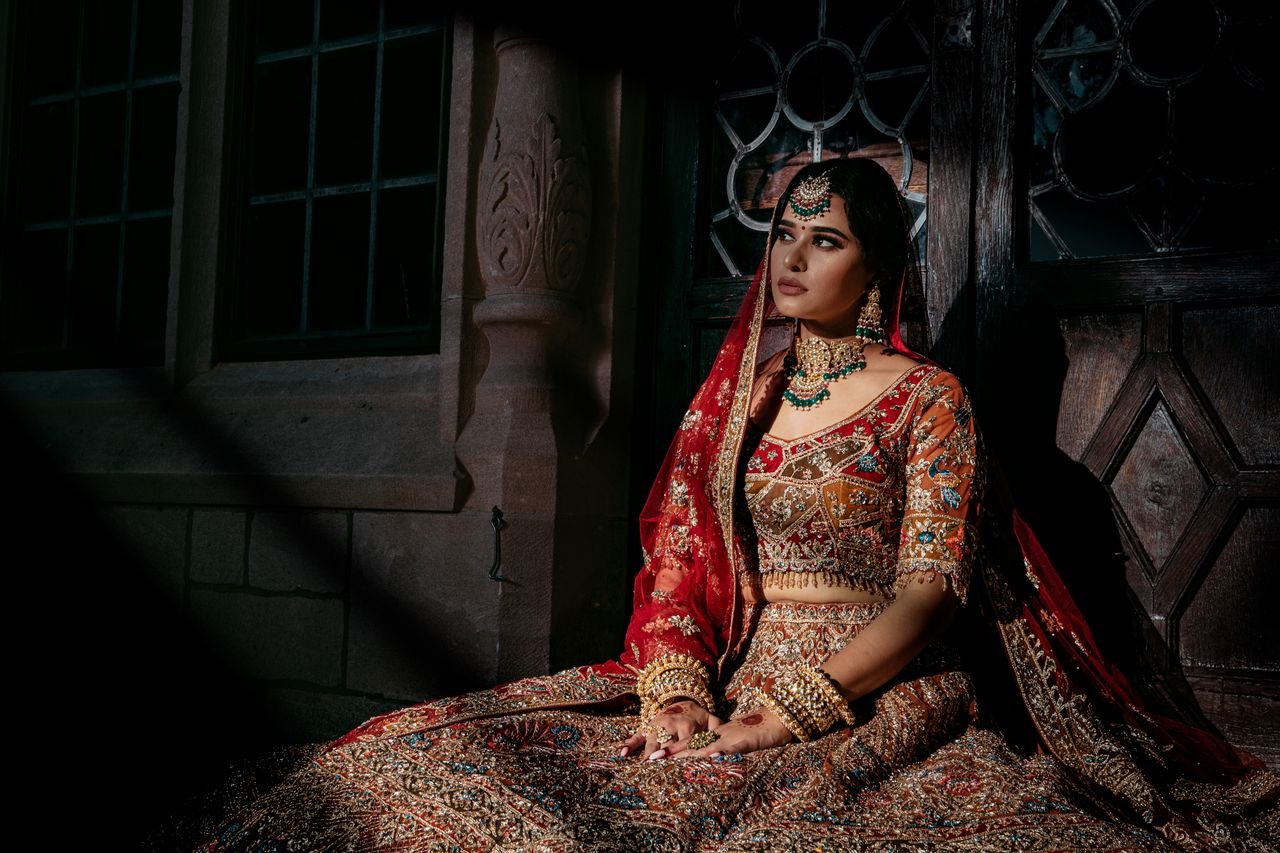 Elegant South Asian bride wearing a red and gold embroidered lehenga.